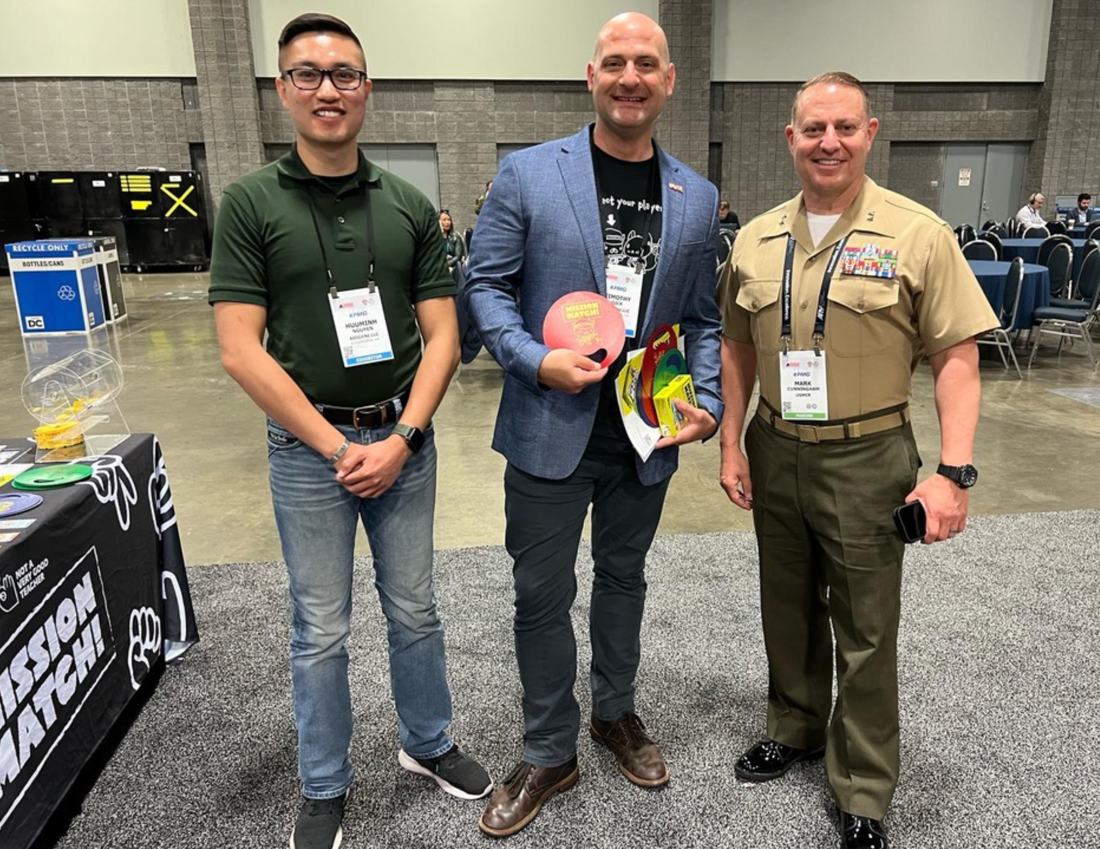 Tim Gick in a blazer holding a Mission Match deck at an expo